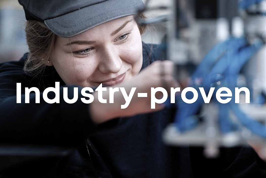 Female technician adjusting industrial machinery, text “Industry Proven