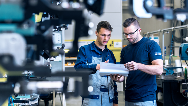 Global implementation: Two technicians discuss a technical drawing in an industrial production environment in order to implement standardised solutions worldwide.
